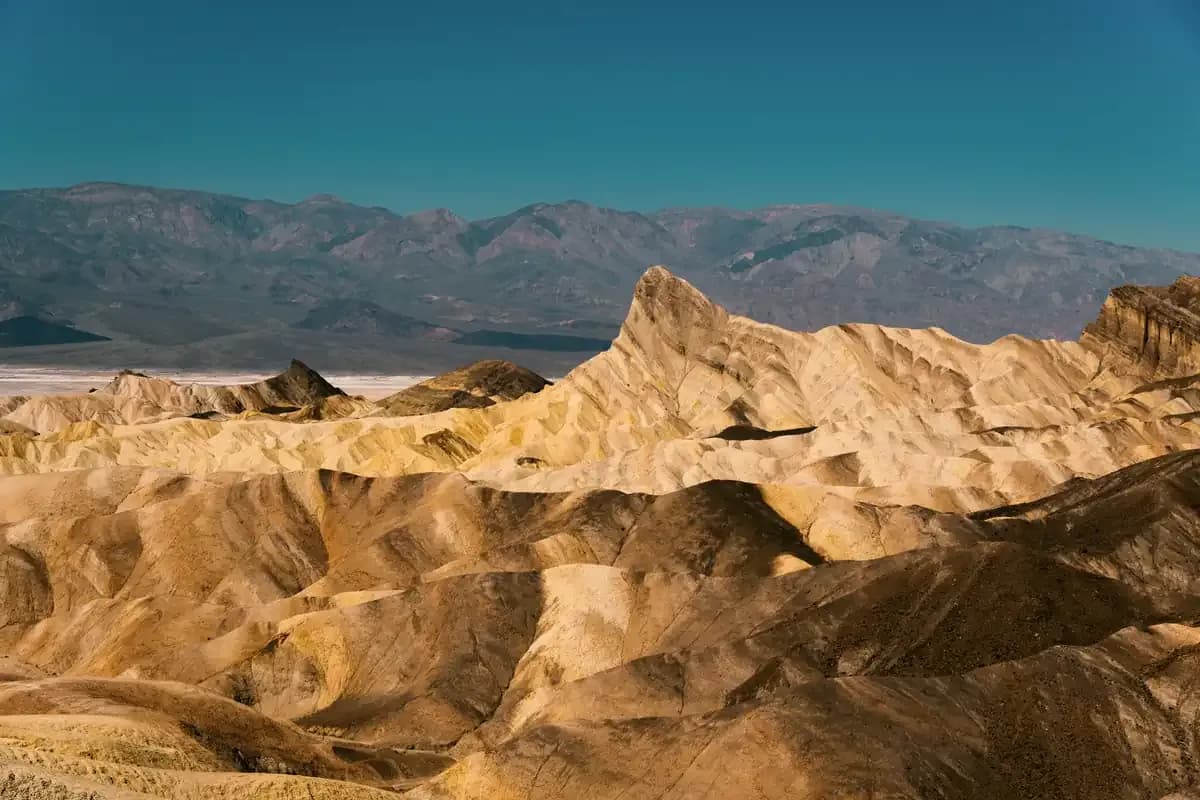 Sunlit desert badlands ridged with shadow under a deep blue sky
