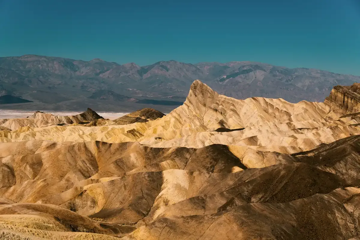 Sunlit desert badlands ridged with shadow under a deep blue sky